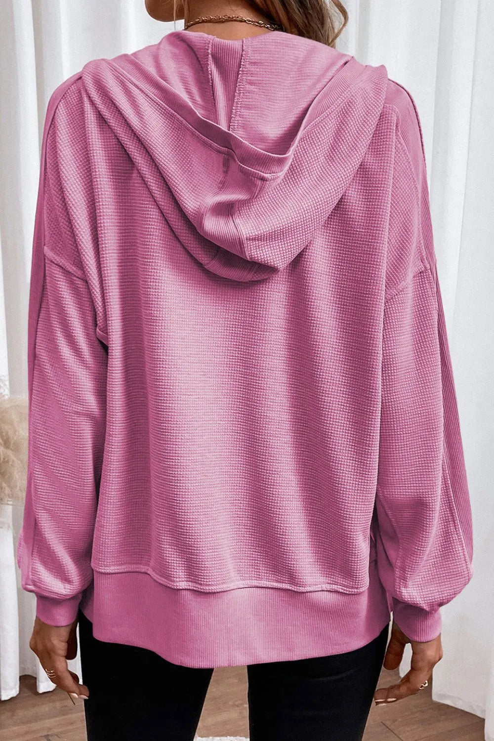 Rear view of a soft pink waffle-knit zip-up hooded jacket with long sleeves.