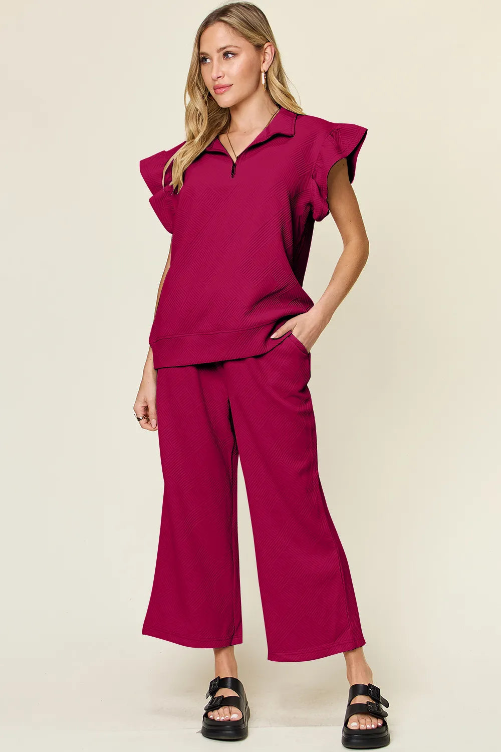 Woman modeling a textured ruffle short sleeve top and wide leg pants set in deep red.