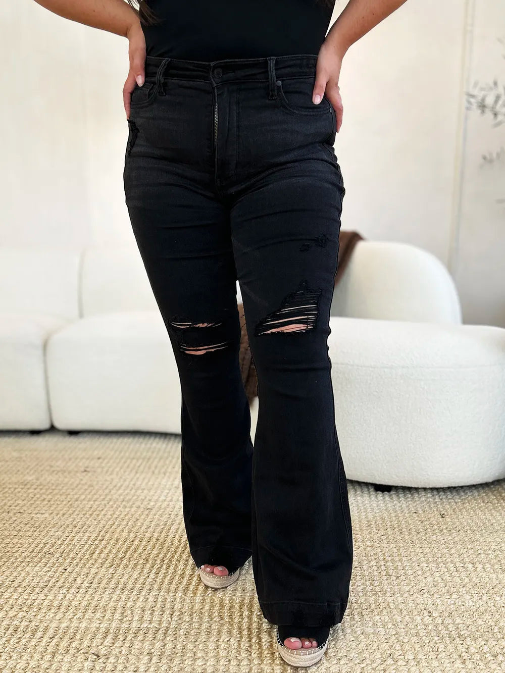 Woman modeling black Judy Blue high-waist distressed flare jeans with rips on thighs.
