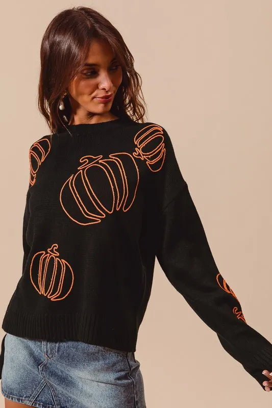 Black knit sweater with orange embroidered pumpkin motifs and long sleeves.
