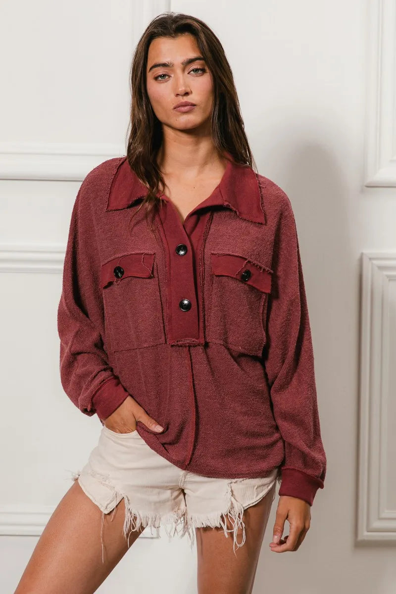 Oversized maroon French terry collared top with buttons and pockets, modeled on a woman.