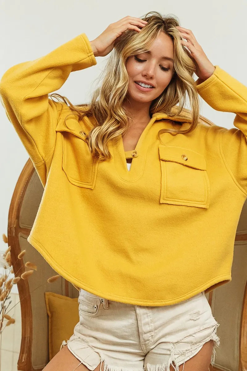 Mustard fleece collared sweatshirt with flap pockets, modeled on a woman.