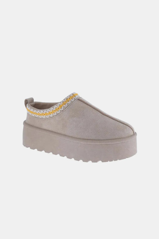Gray suede platform slip-on boots with yellow embroidered trim.