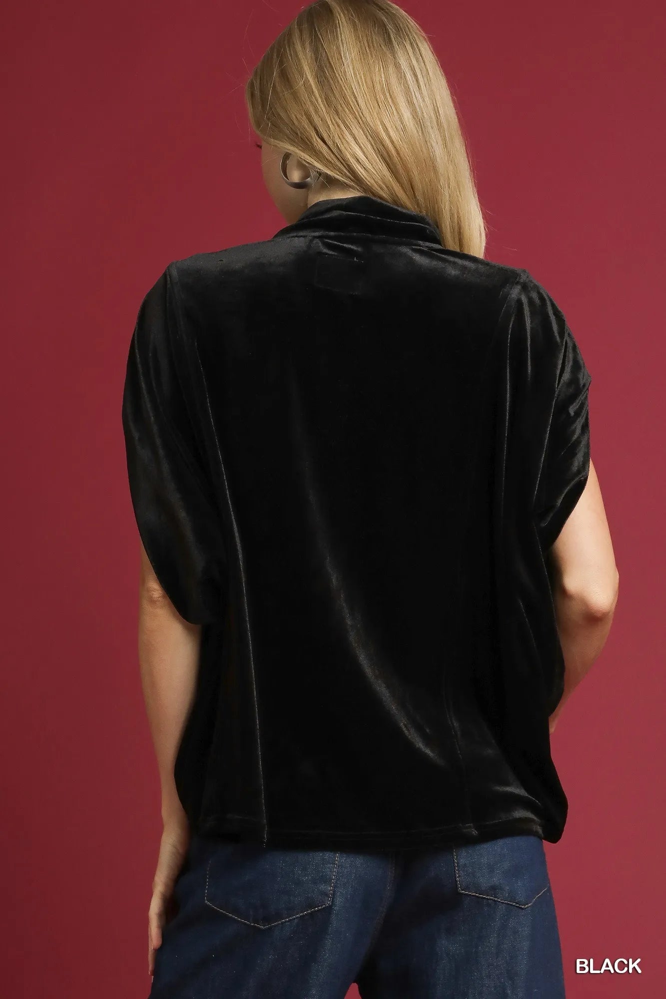 Rear view of a black velvet mock neck sleeveless blouse on a model.