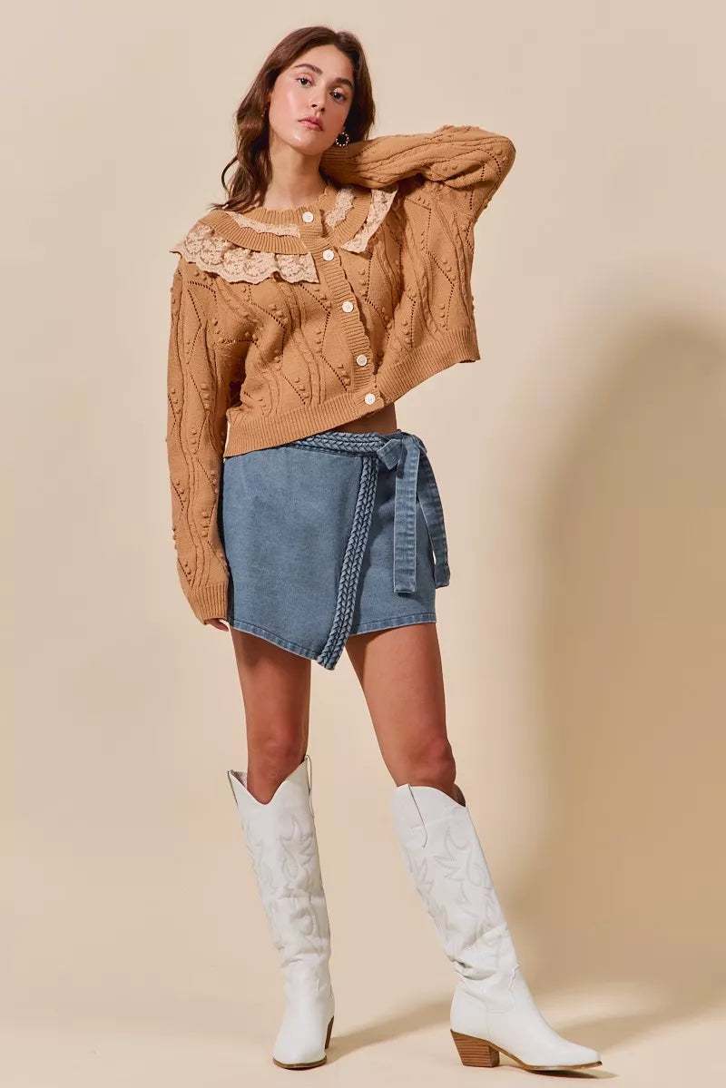 Woman modeling a wrap braided trim denim skort with asymmetrical design and tie belt.