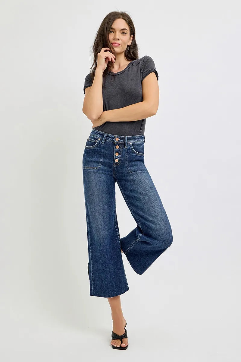 Model poses in RISEN high-rise wide-leg crop jeans in medium wash, paired with a gray short-sleeve top and black slingback heels.