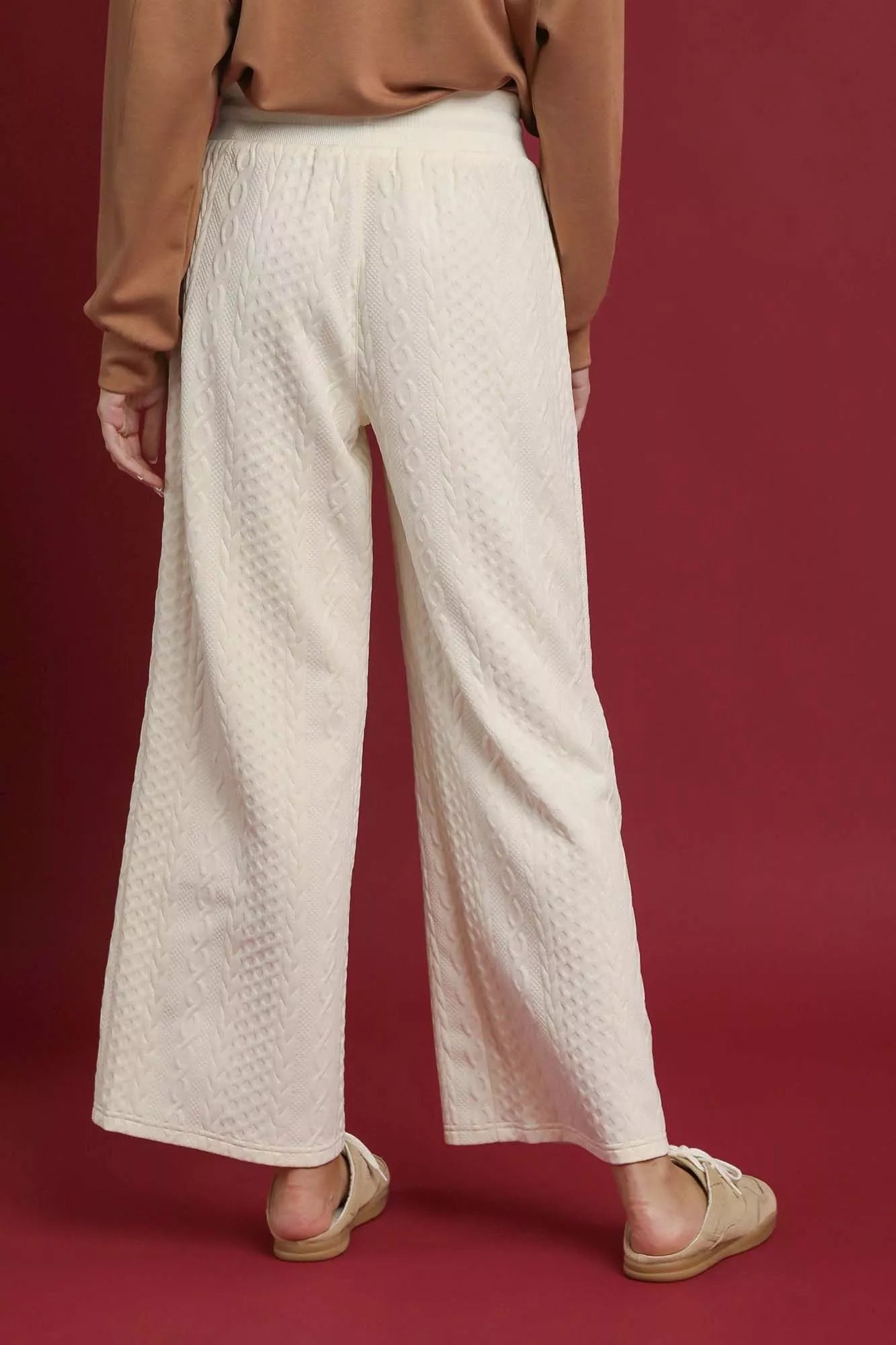 Rear view of cream cable knit textured wide leg pants with drawstring waist.