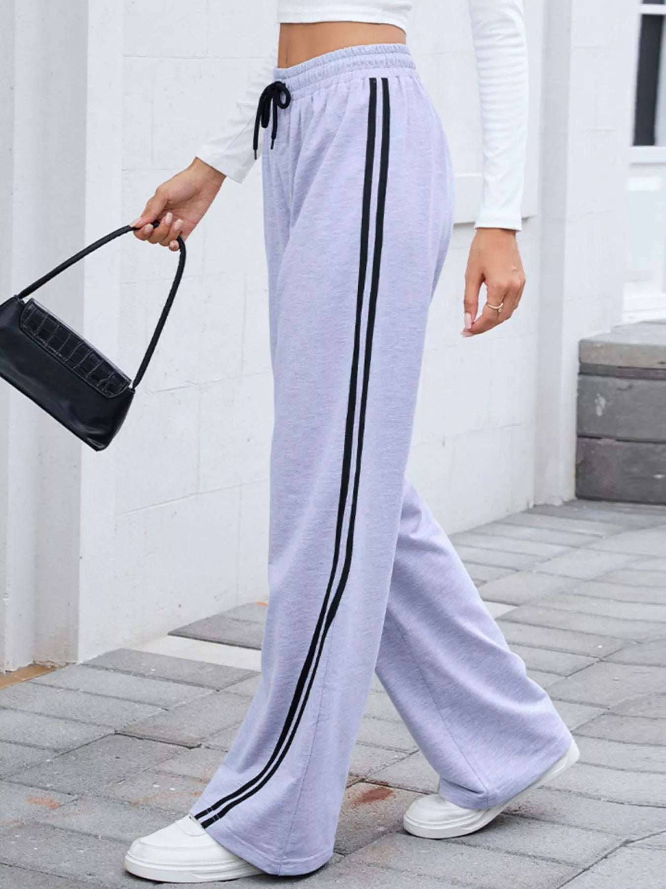 Gray rayon blend wide leg pants with black side stripes and drawstring waist, modeled on a woman.