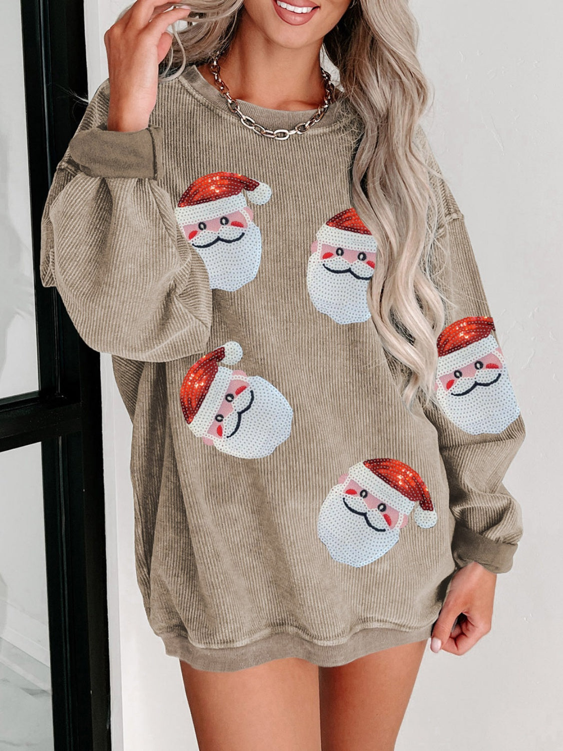 Tan ribbed sweatshirt with sequin Santa patches and long sleeves.