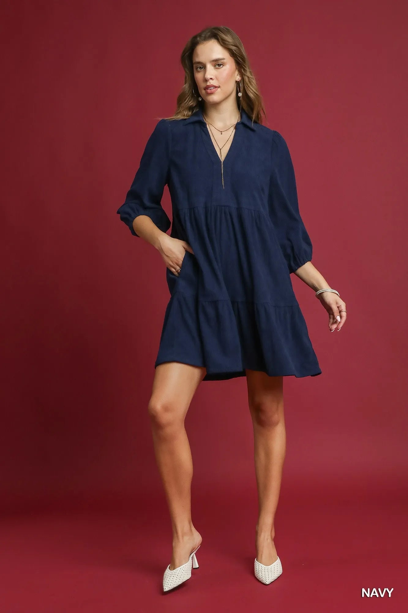Woman modeling navy tiered corduroy mini dress with balloon sleeves and collar.