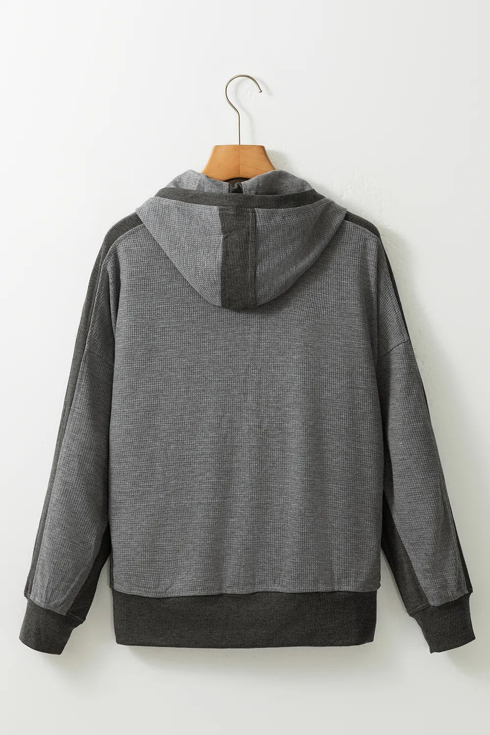 Back view of soft pink waffle-knit zip-up hooded jacket on hanger.