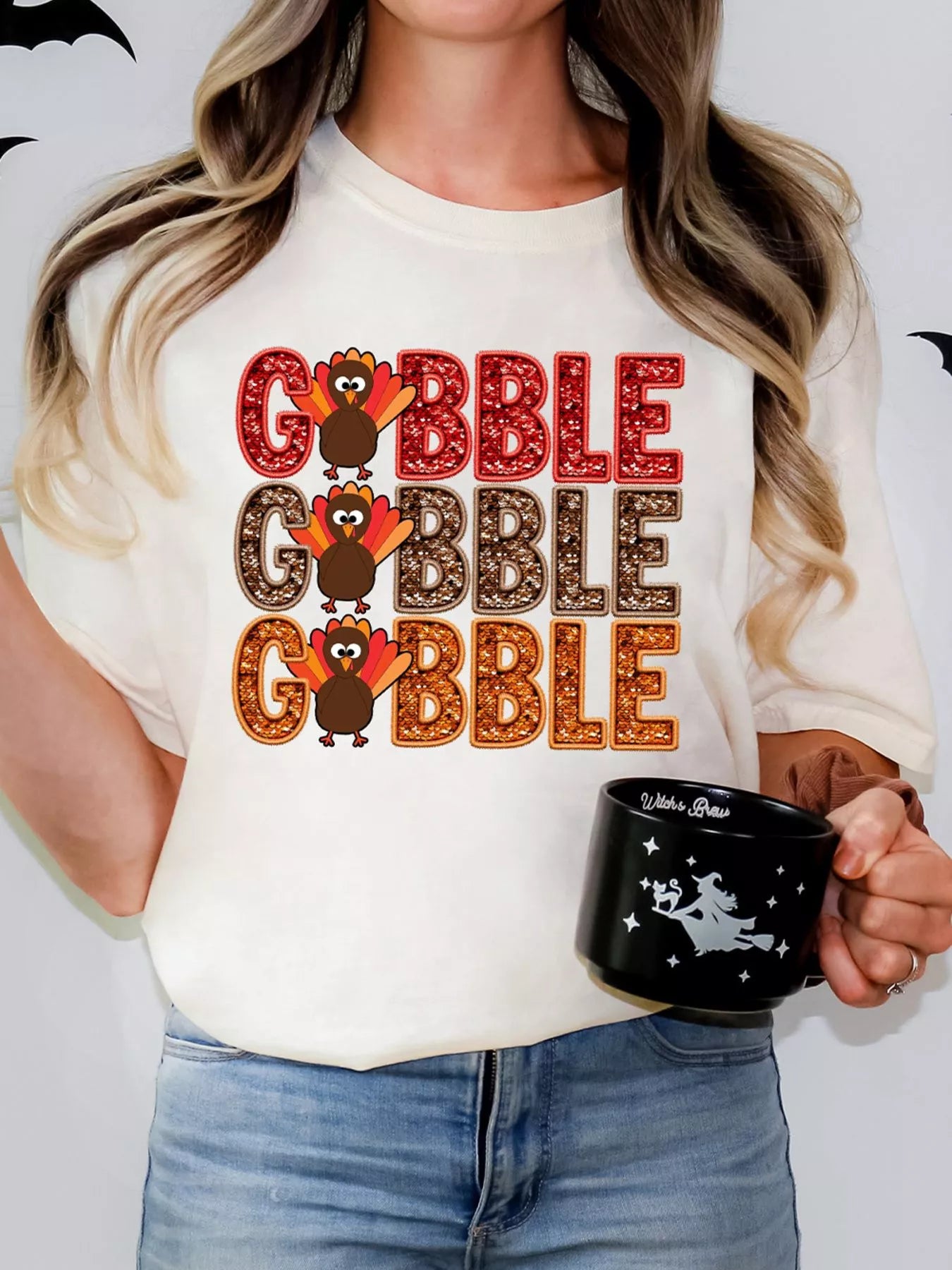 Woman wearing a white poly-cotton T-shirt with stacked "Gobble" text and turkey prints.