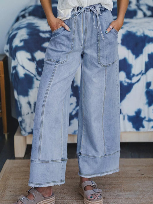 Light wash wide-leg jeans with drawstring waist, pockets, and raw hem.
