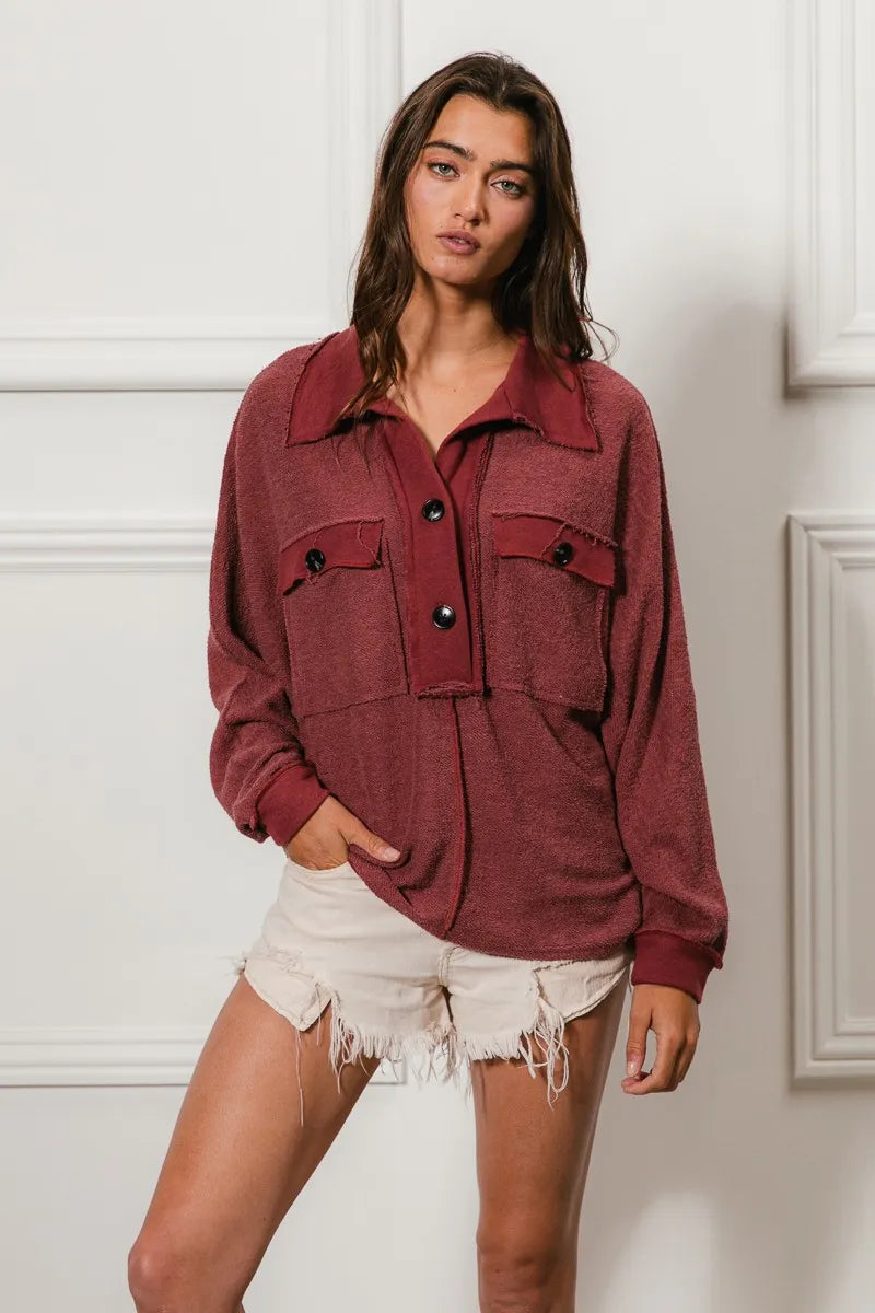 Oversized maroon French terry collared top with buttons and pockets, modeled on a woman.