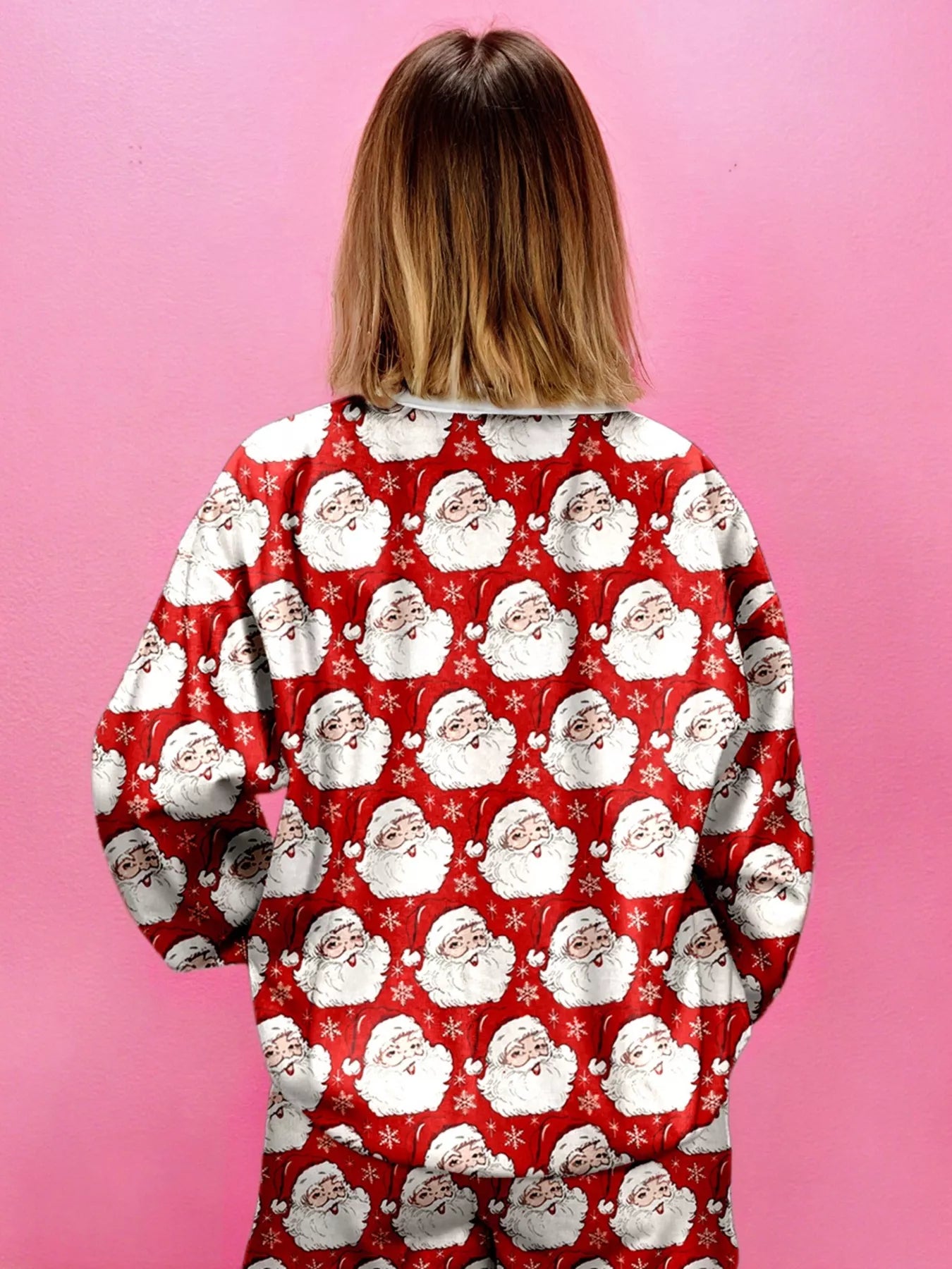 Back view of a woman wearing a pink two-piece lounge set with Santa print.