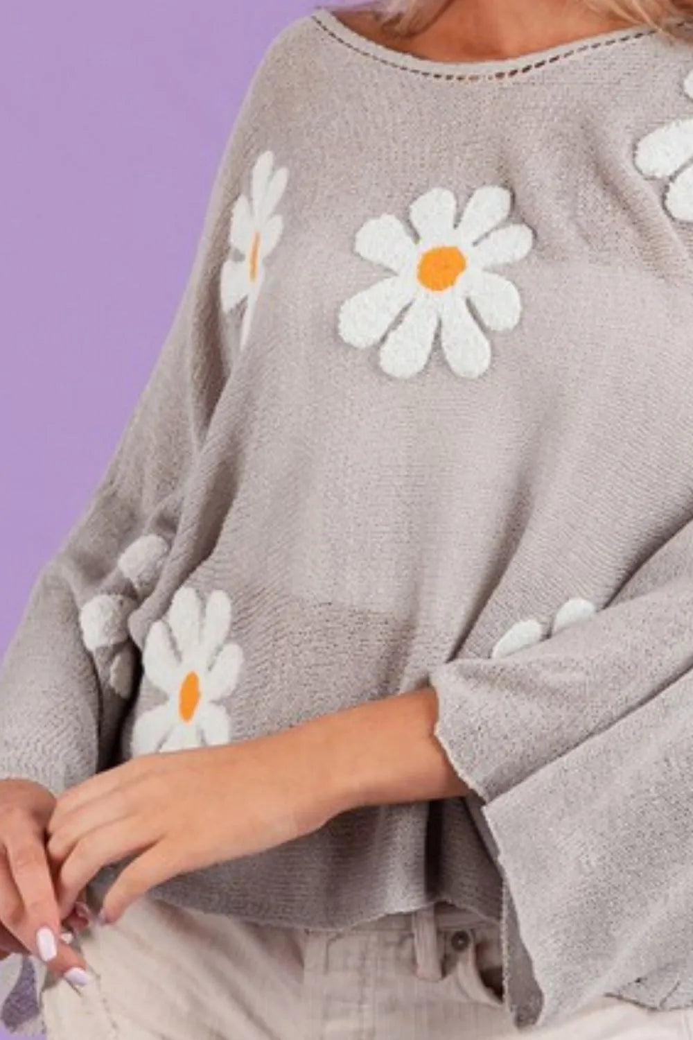 Gray loose fit knit top with embroidered white and yellow daisies and bell sleeves.