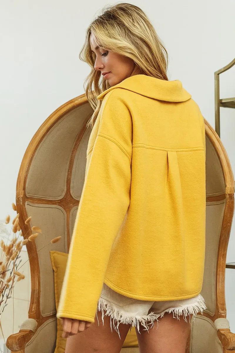 Rear view of mustard fleece collared sweatshirt with flap pockets on model.