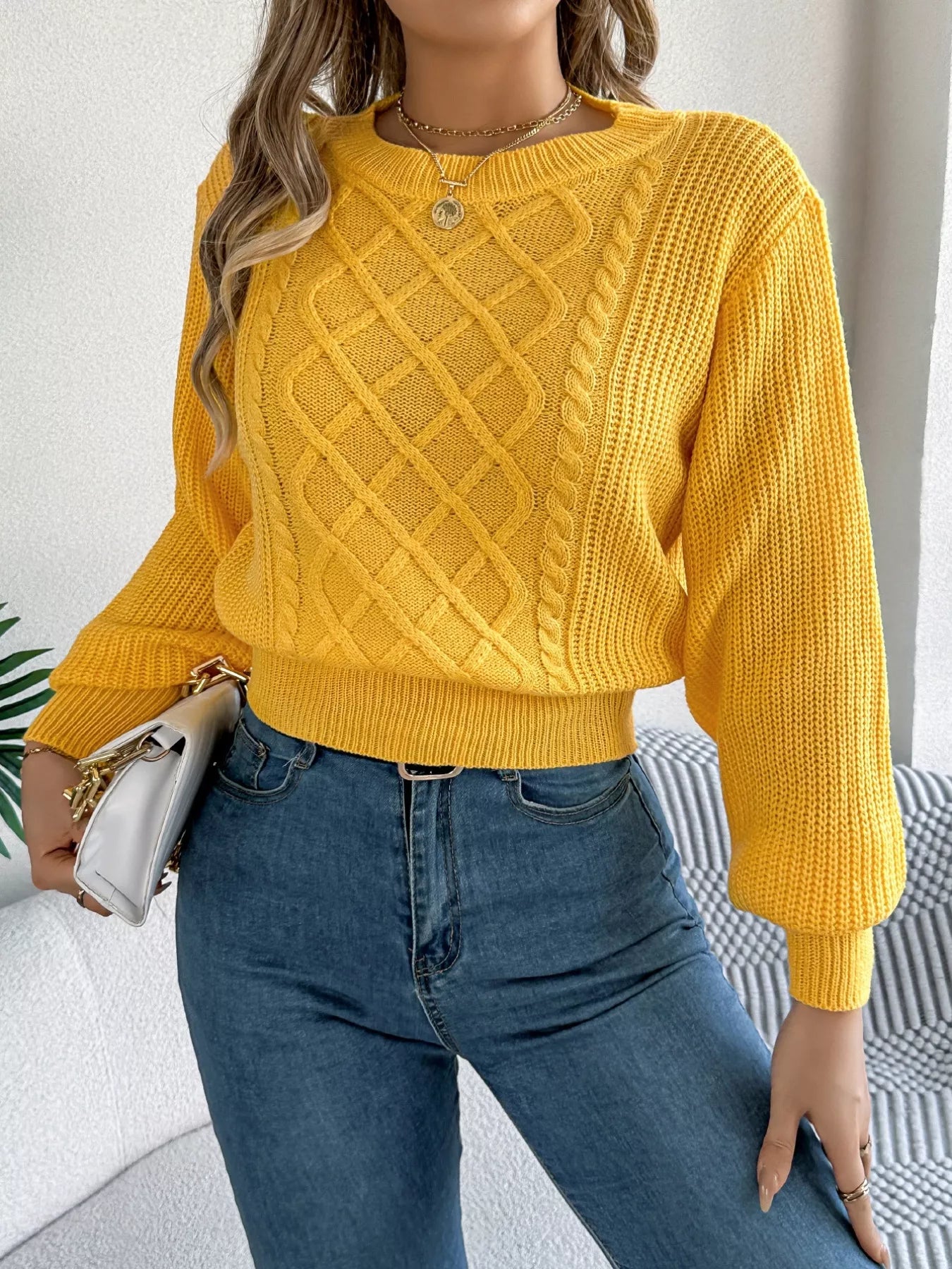A cream cable knit sweater with a diamond pattern and long sleeves made from acrylic blend.