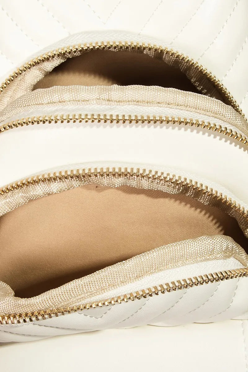 White quilted faux leather sling bag with gold zippers and open compartments.