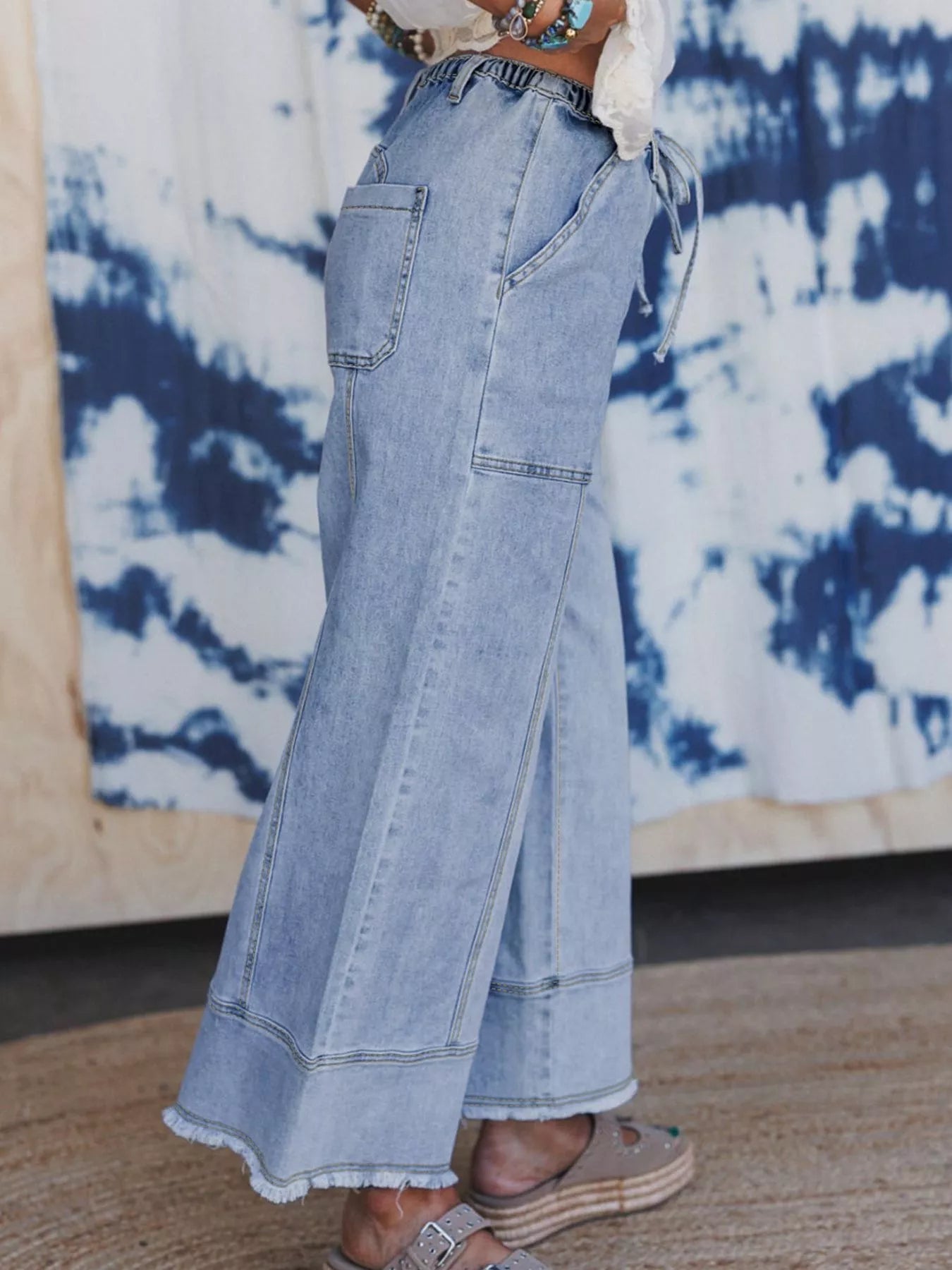 Light wash wide-leg drawstring jeans with raw hem and pockets, model wearing size 4.