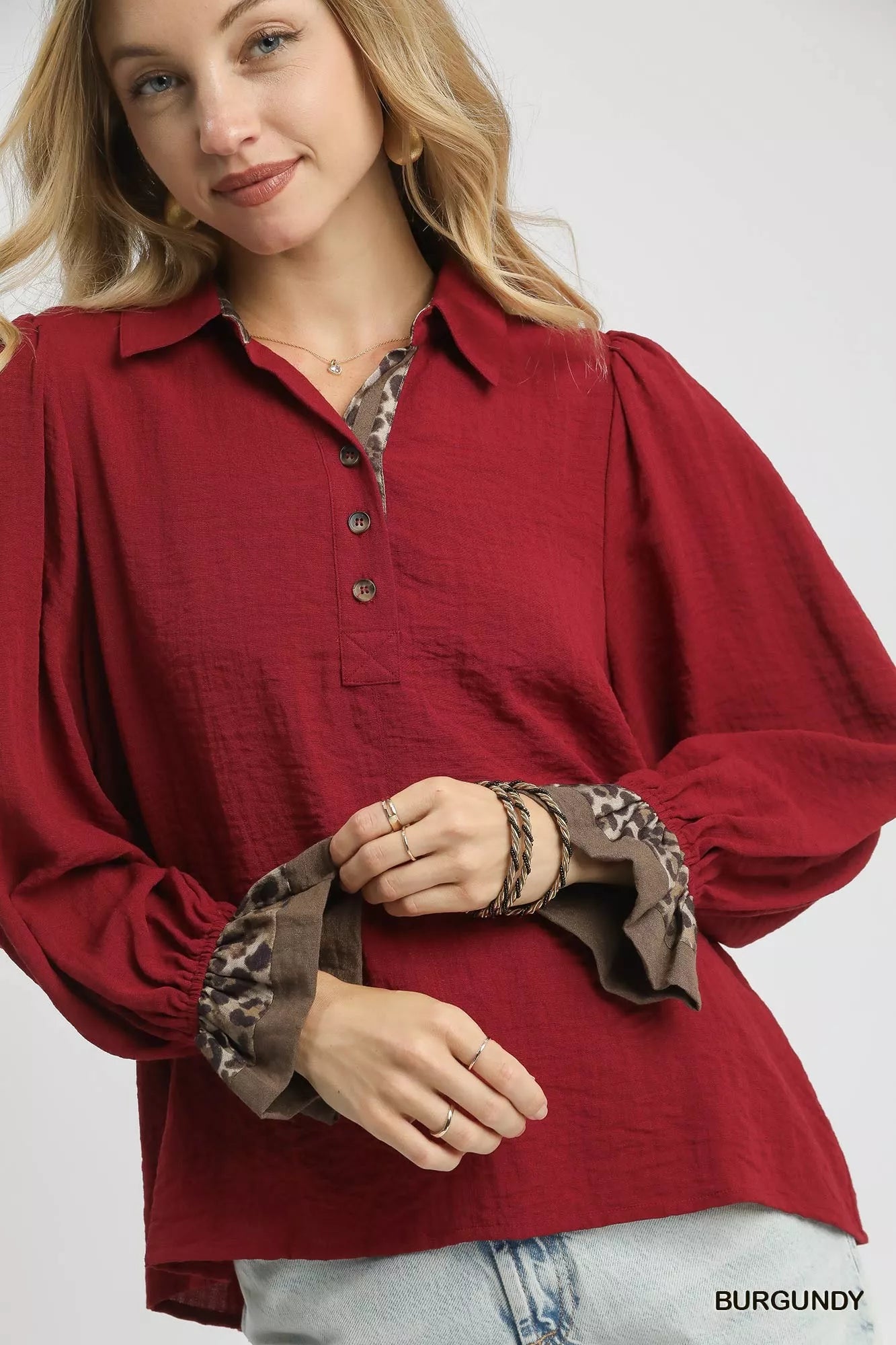 Burgundy half-button blouse with leopard print trim on cuffs and collar.