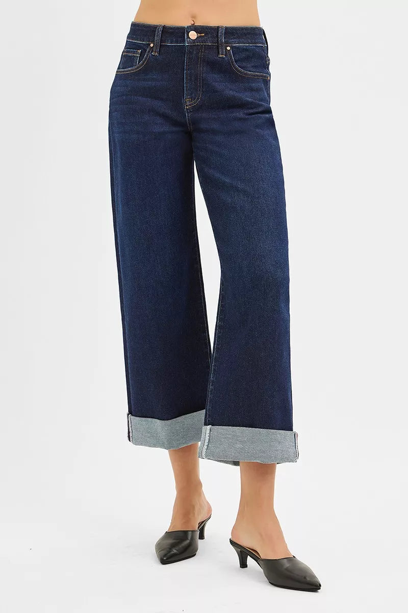 Mid-rise ankle wide-leg jeans in dark wash with rolled cuffs, modeled on a woman wearing black heels.