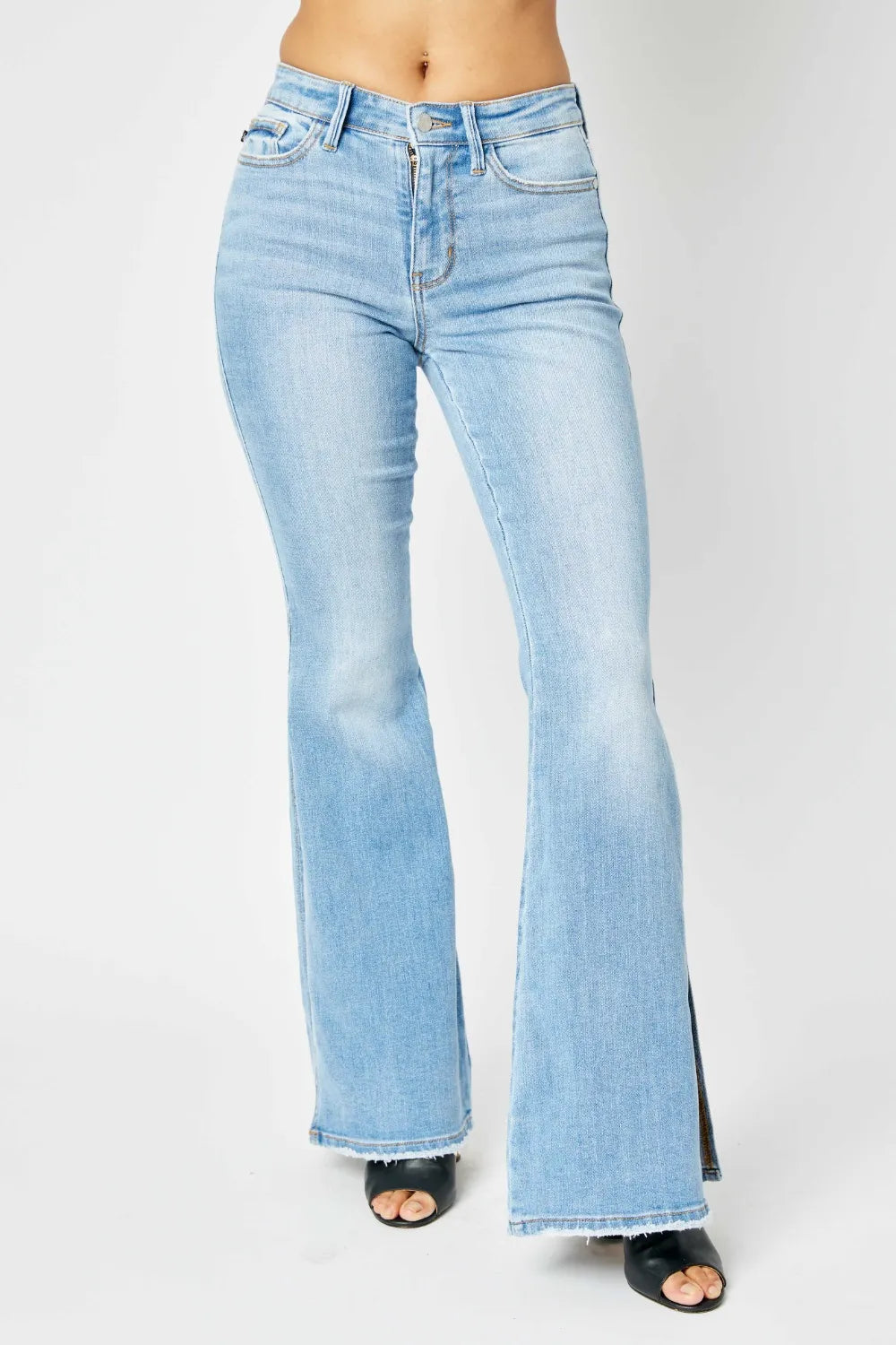 Light wash mid-rise flare jeans with raw hem on a model.