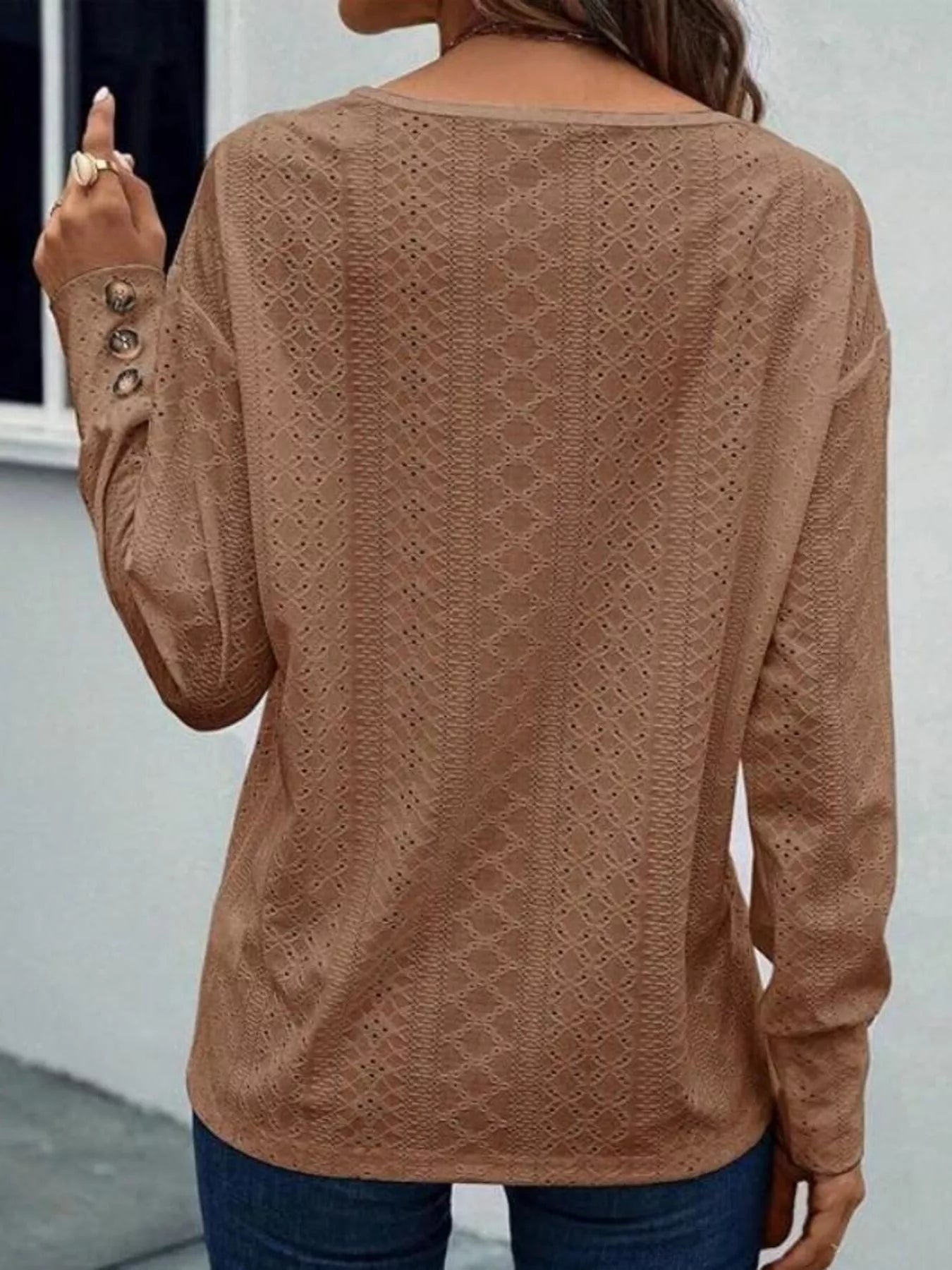 Long sleeve eyelet V-neck blouse in a polyester blend with decorative buttons.