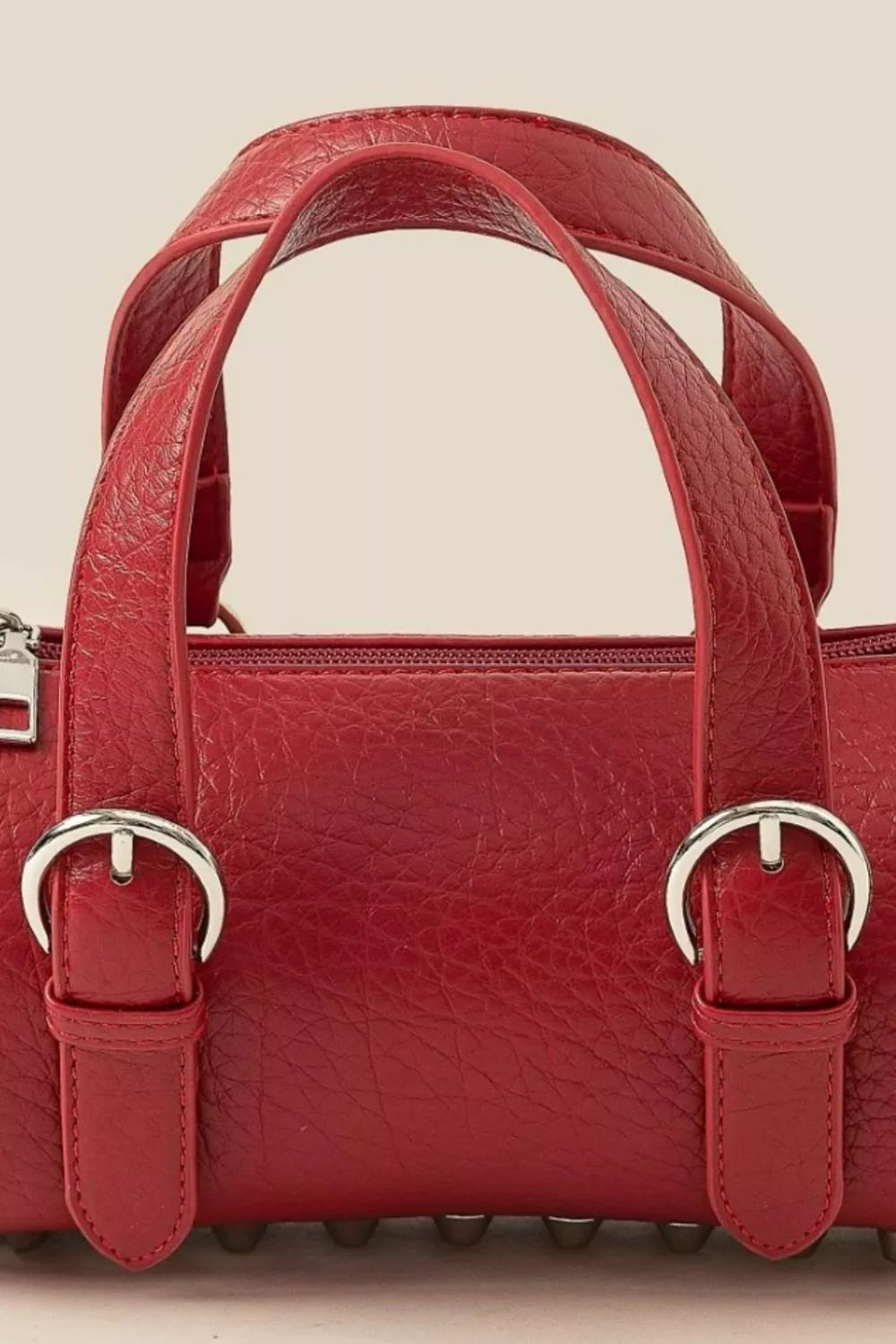 Burgundy faux leather mini cylinder bag with buckle straps and double handles.
