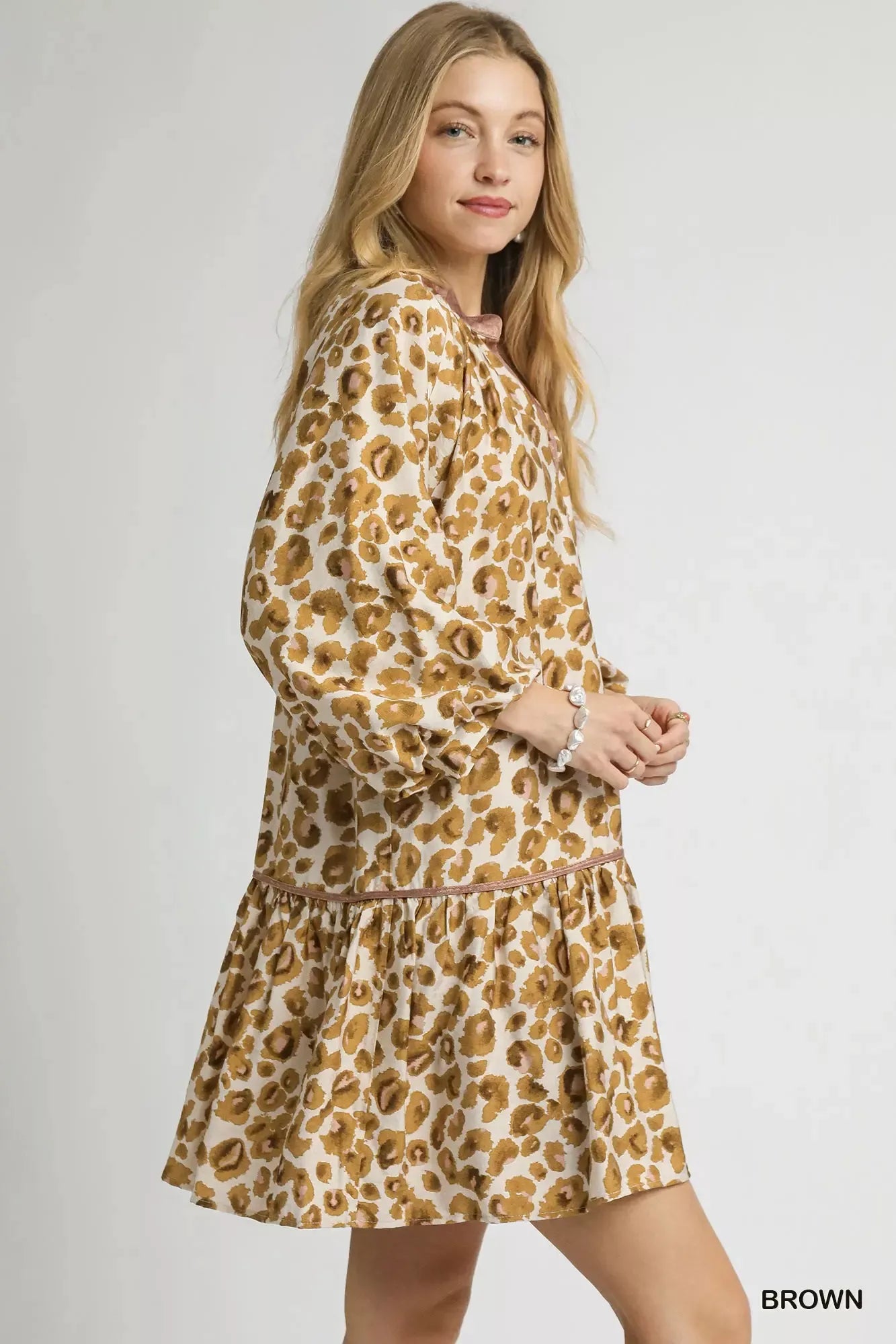 Woman modeling a brown leopard print tiered mini dress with long sleeves and ruffles.