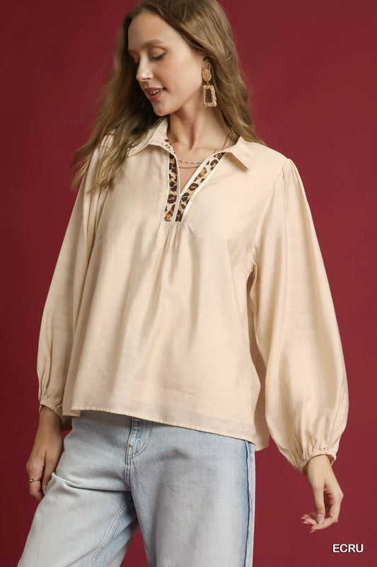 Woman modeling a long-sleeve beige blouse with leopard print trim on collar and cuffs.