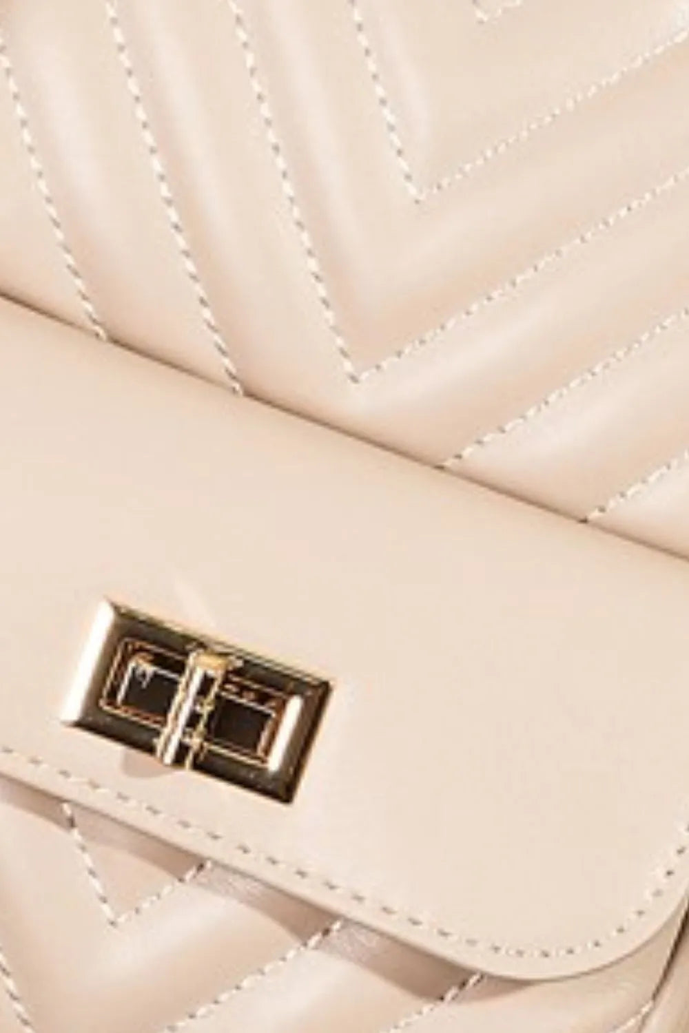 Quilted nude faux leather sling bag with gold turn-lock closure and adjustable strap.