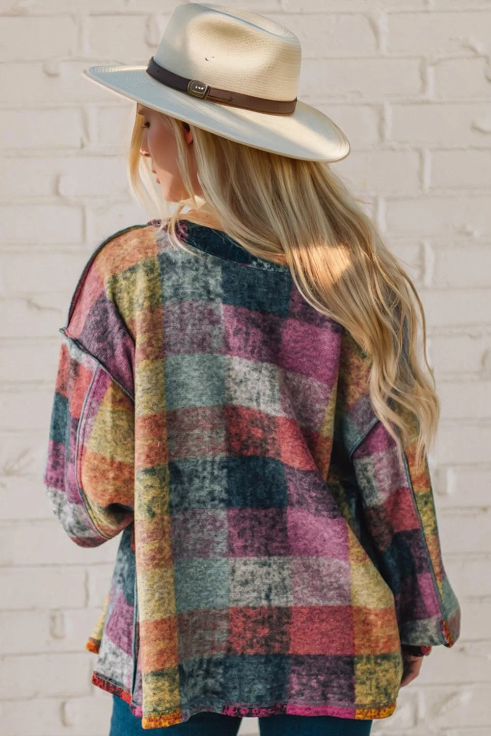 Rear view of a multicolor plaid fleece shacket on a model wearing a beige hat.