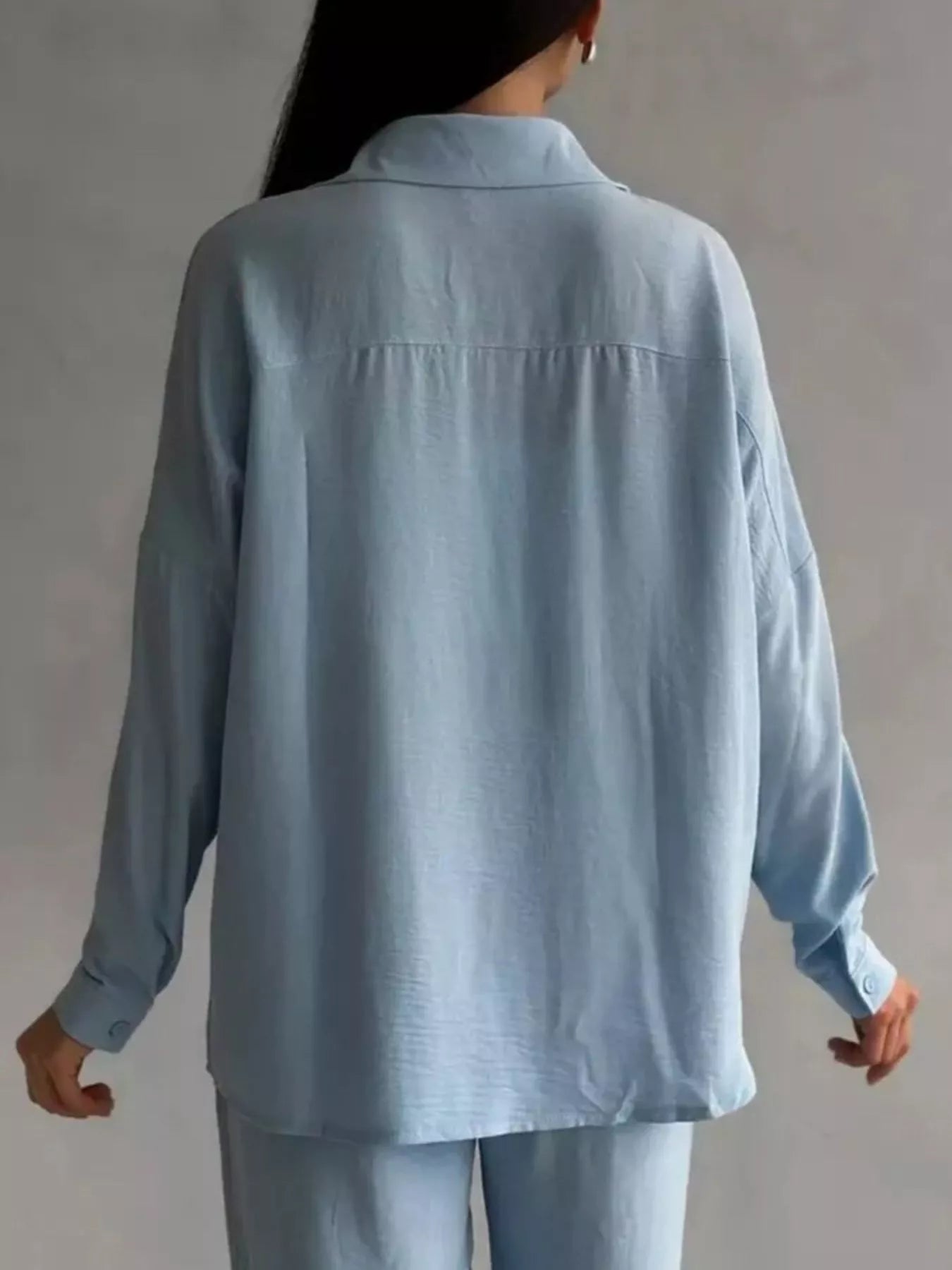 Rear view of a light blue two-piece button-down shirt and pants set on a model.