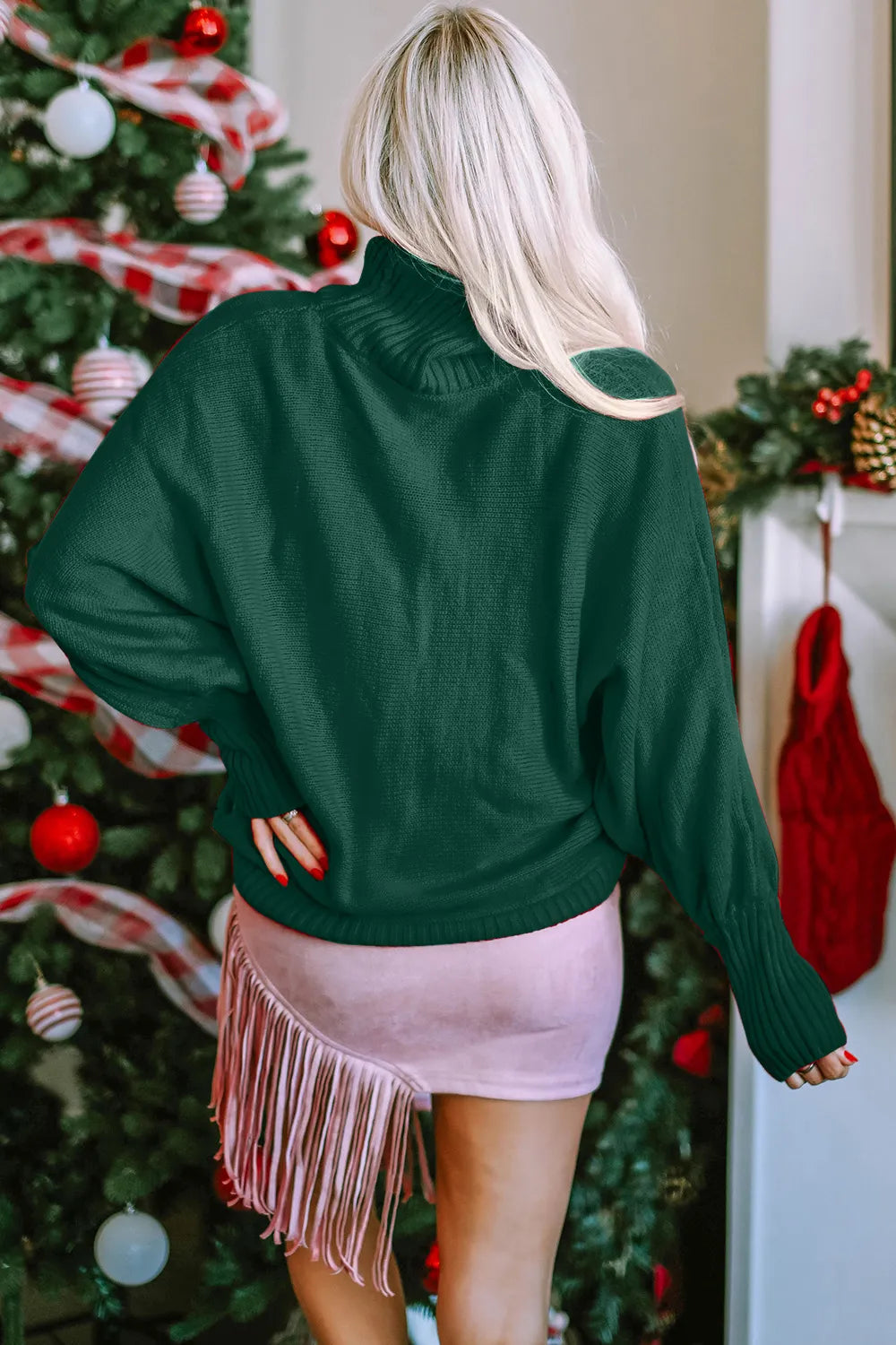 Woman modeling back view of emerald green turtleneck acrylic sweater with moderate stretch.