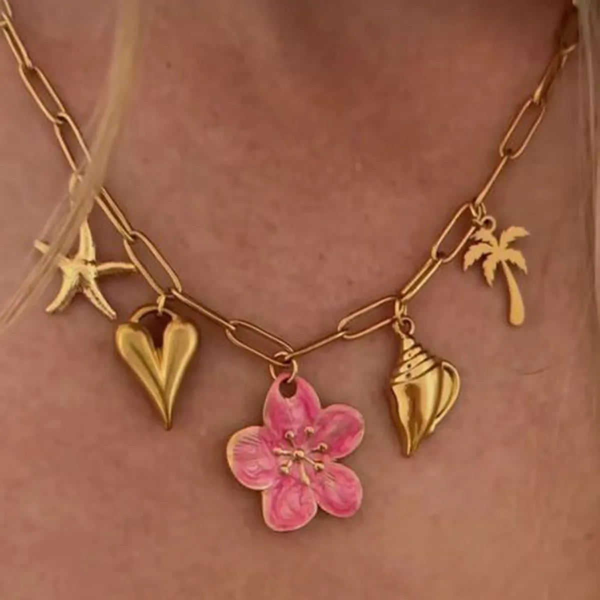 Gold-toned chain necklace with pink resin flower, starfish, heart, seashell, and palm tree pendants.