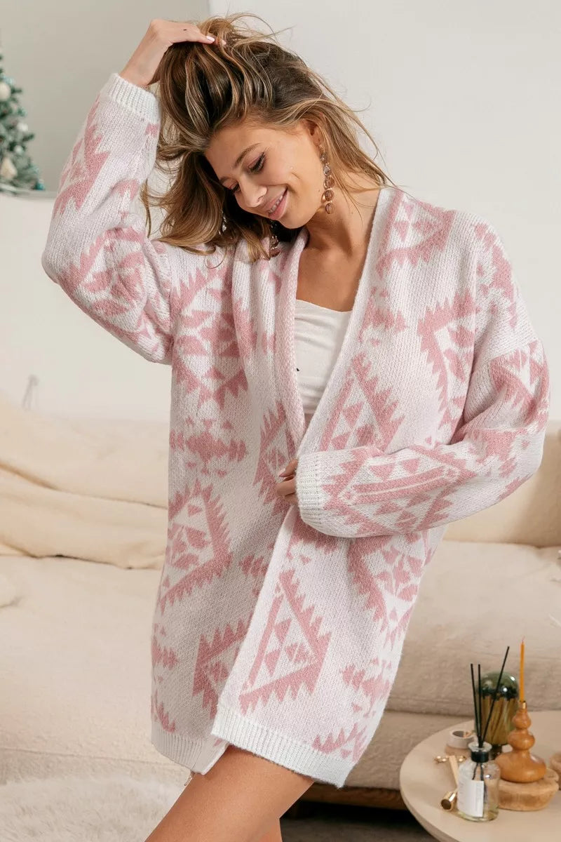Pink open-front acrylic cardigan with Aztec pattern, modeled by a smiling woman.