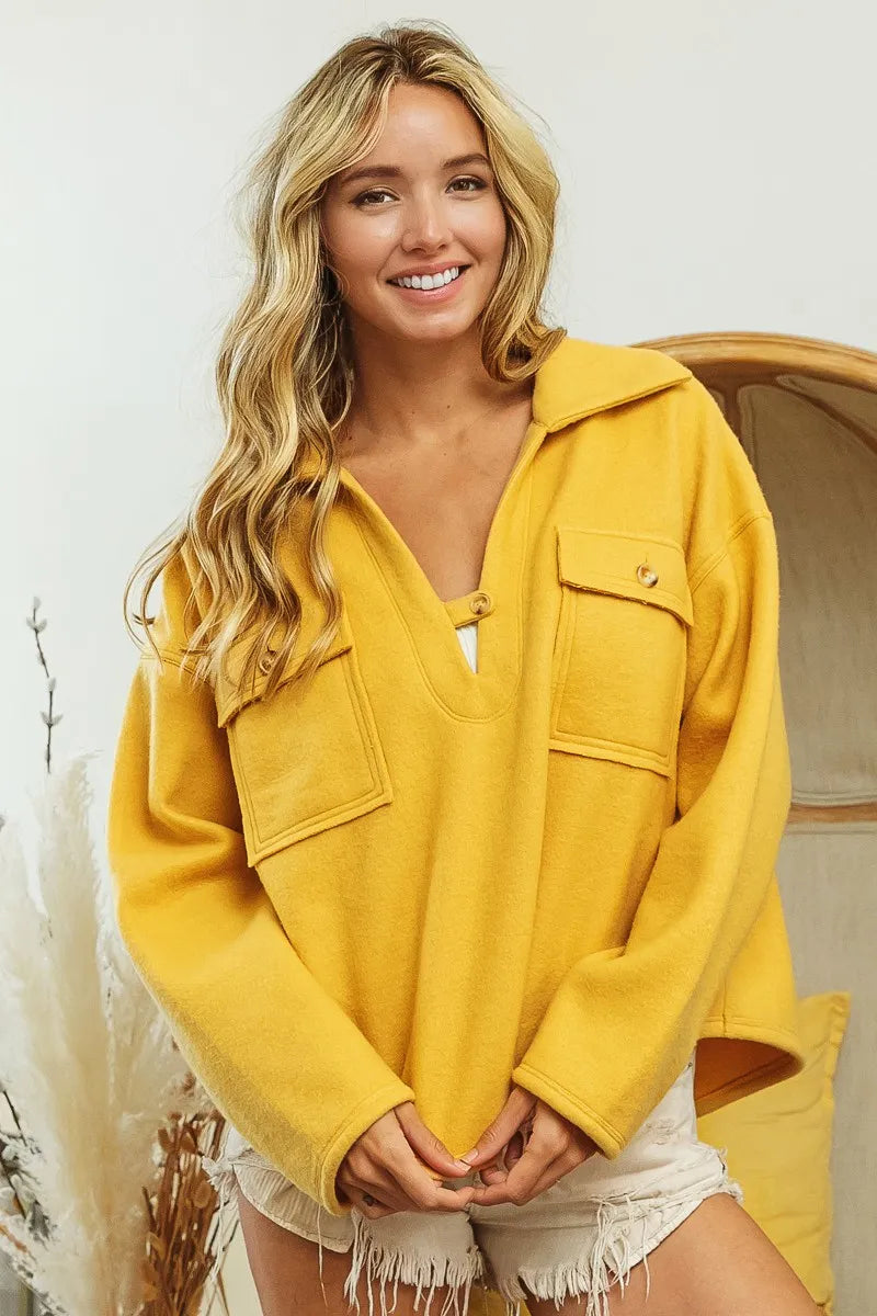 Mustard fleece collared sweatshirt with flap pockets modeled on a smiling woman.