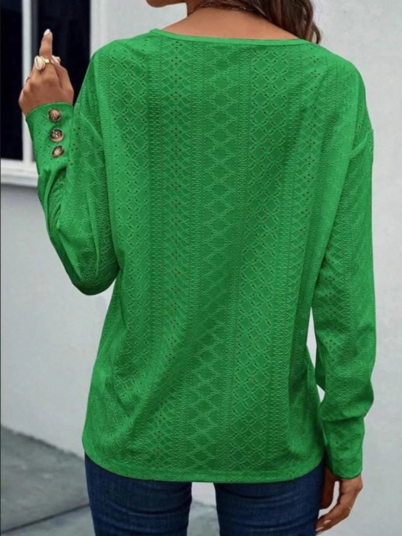 Long sleeve eyelet V-neck blouse in a polyester blend with decorative buttons.
