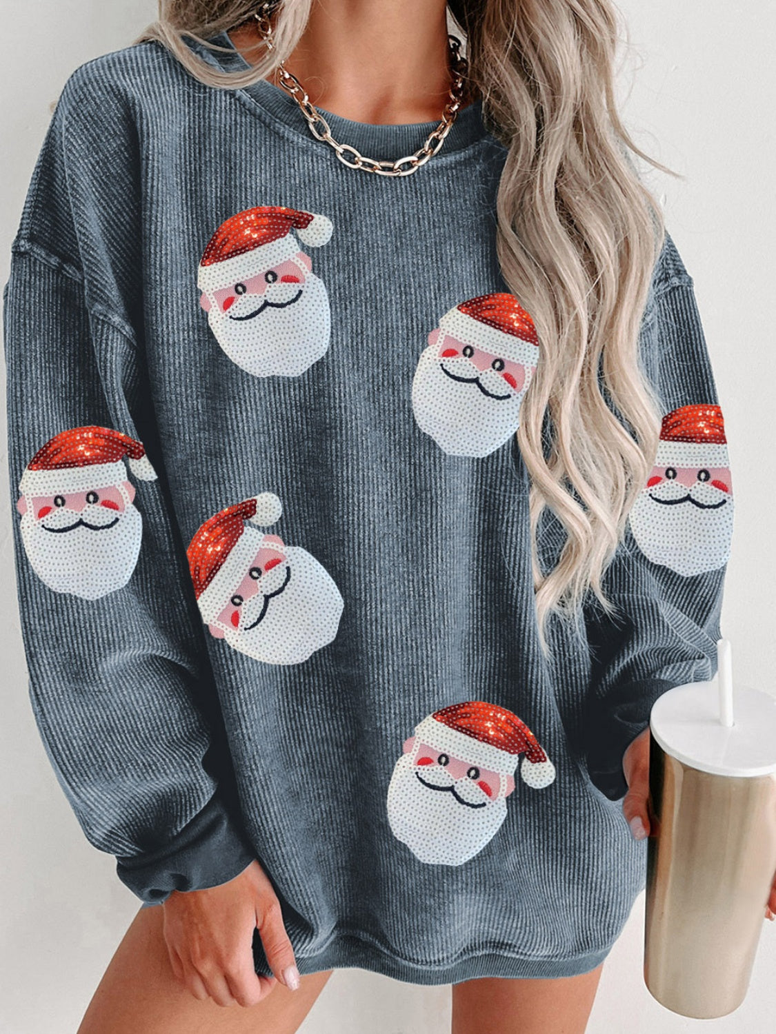 Gray ribbed sweatshirt with sequin Santa patches and long sleeves, modeled by a woman holding a tumbler.