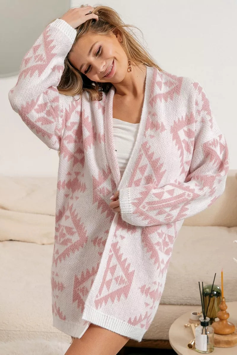 Pink acrylic open-front cardigan with Aztec pattern, modeled by a smiling woman.