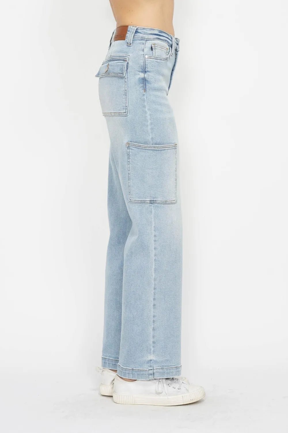 High-waist straight-leg cargo jeans in light wash with multiple pockets, modeled from the side.