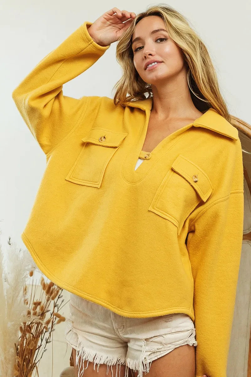 Mustard fleece collared sweatshirt with flap pockets modeled on a woman.
