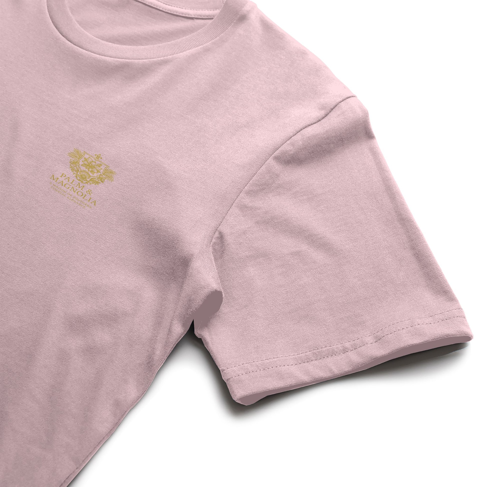 Pink Bella Canvas T-shirt with gold embroidered magnolia blossom on chest.