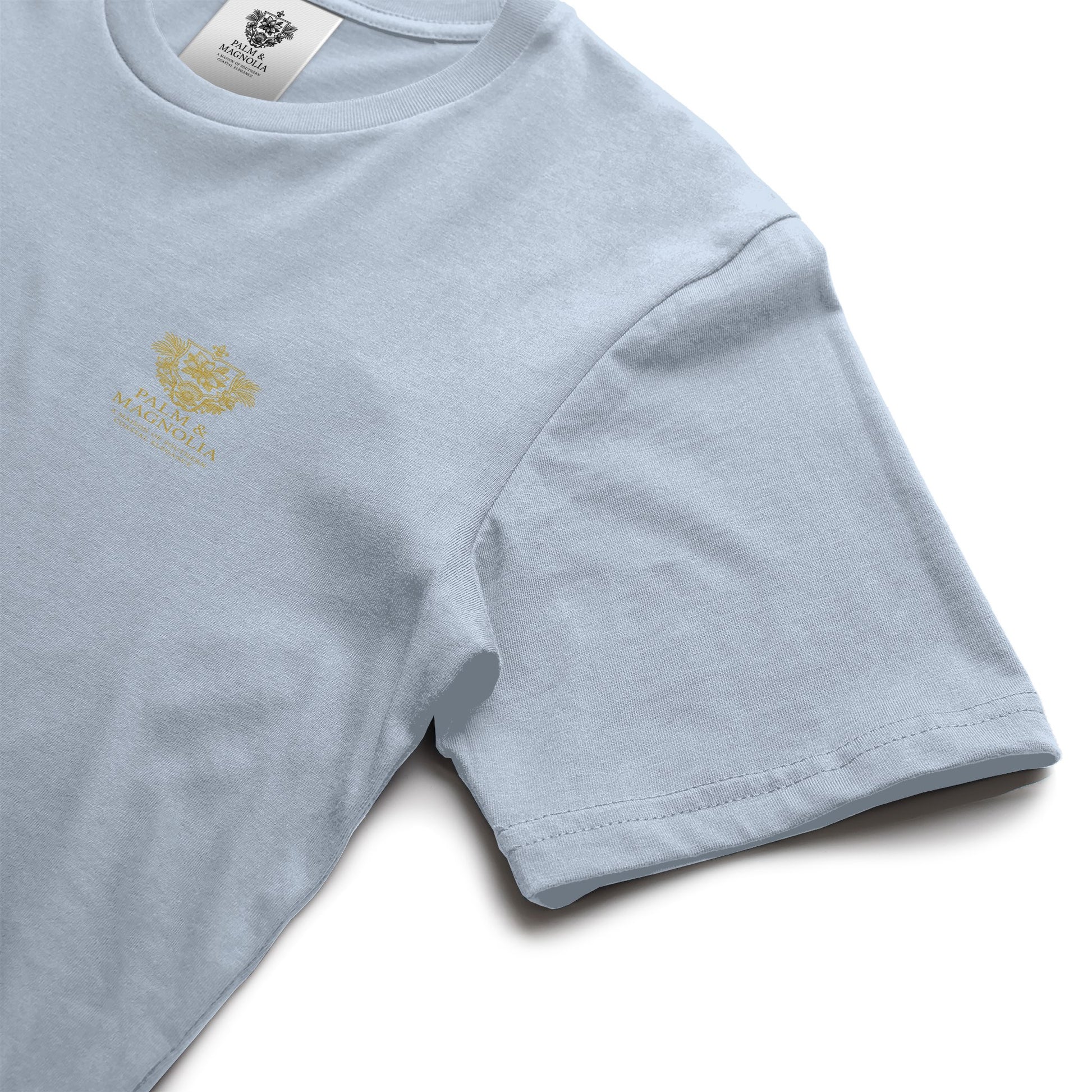 Light blue unisex ring-spun cotton tee with gold Palm & Magnolia emblem.