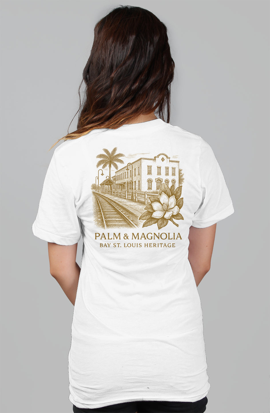 Back view of white women's relaxed tee with gold Palm & Magnolia Bay St. Louis crest.