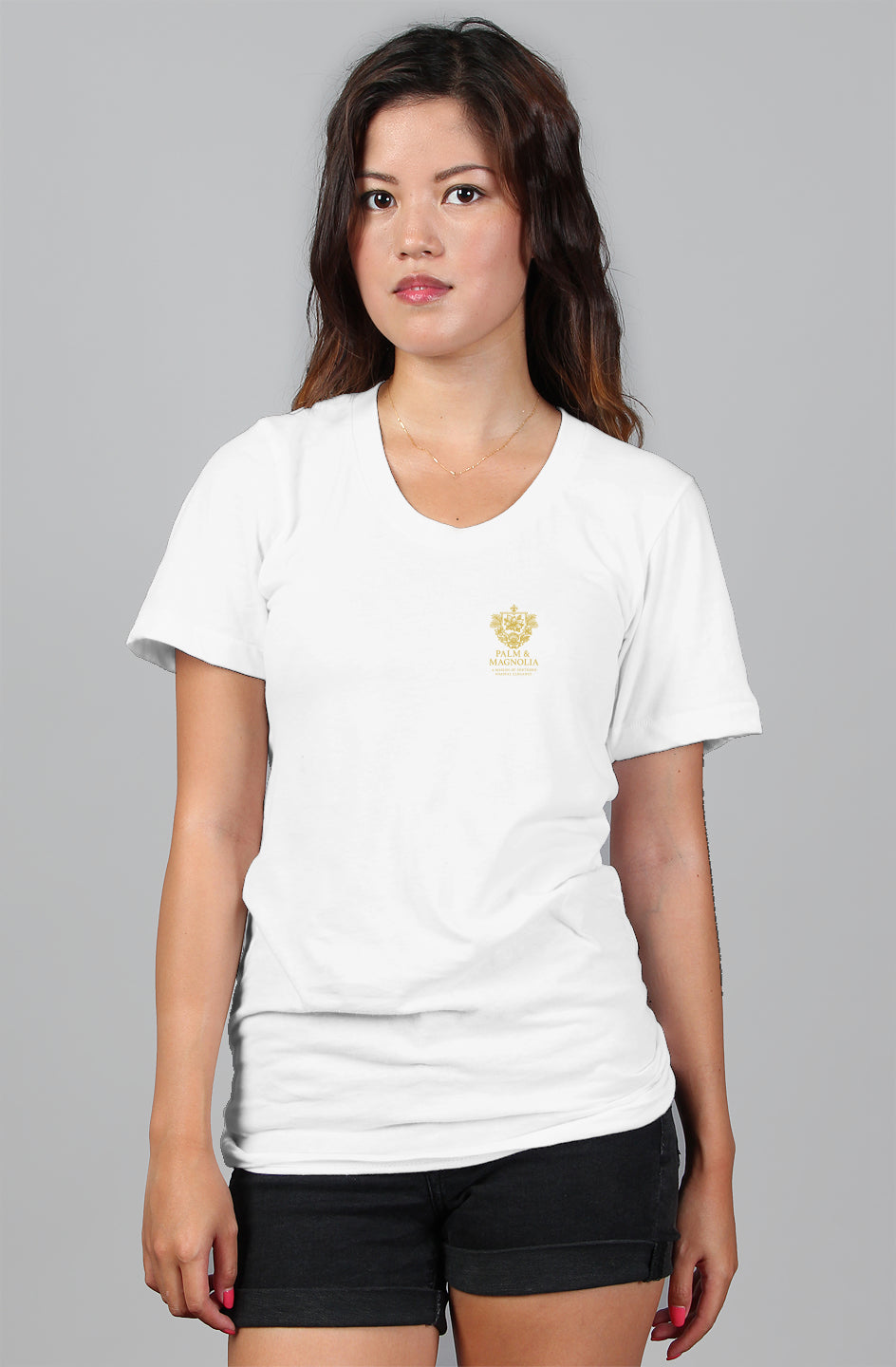 Woman modeling white relaxed-fit women's tee with gold crown emblem on chest.