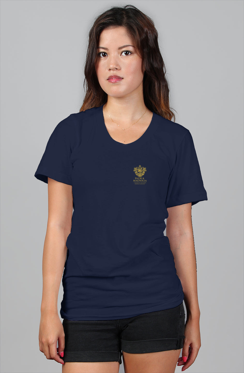 Woman modeling navy relaxed-fit women's tee with gold Gulfport Harbor Heritage emblem.