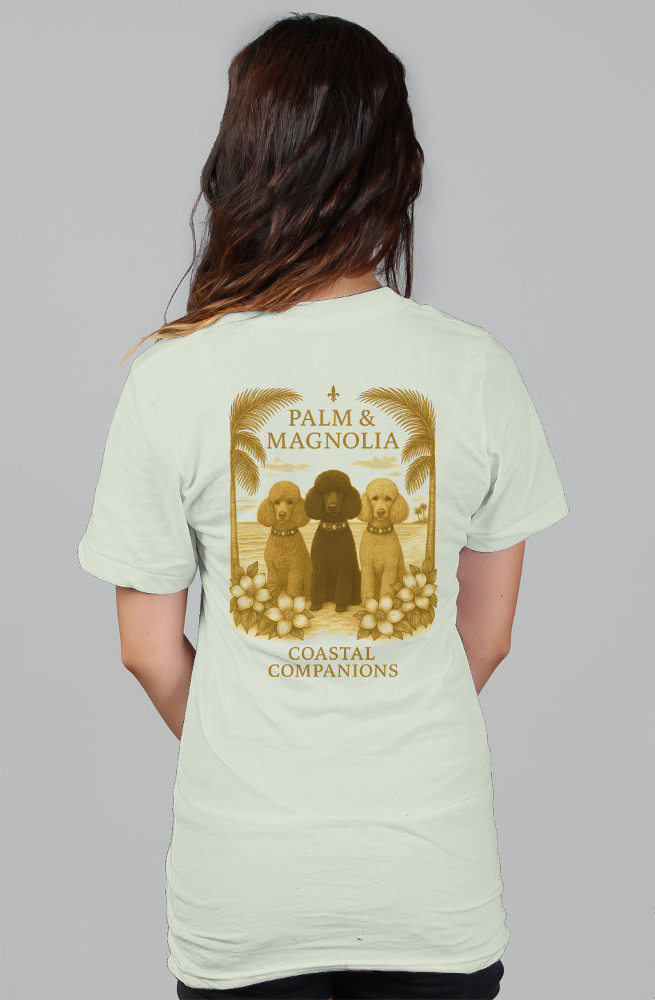 Back view of a relaxed women's tee with three poodles framed by palms and magnolias.