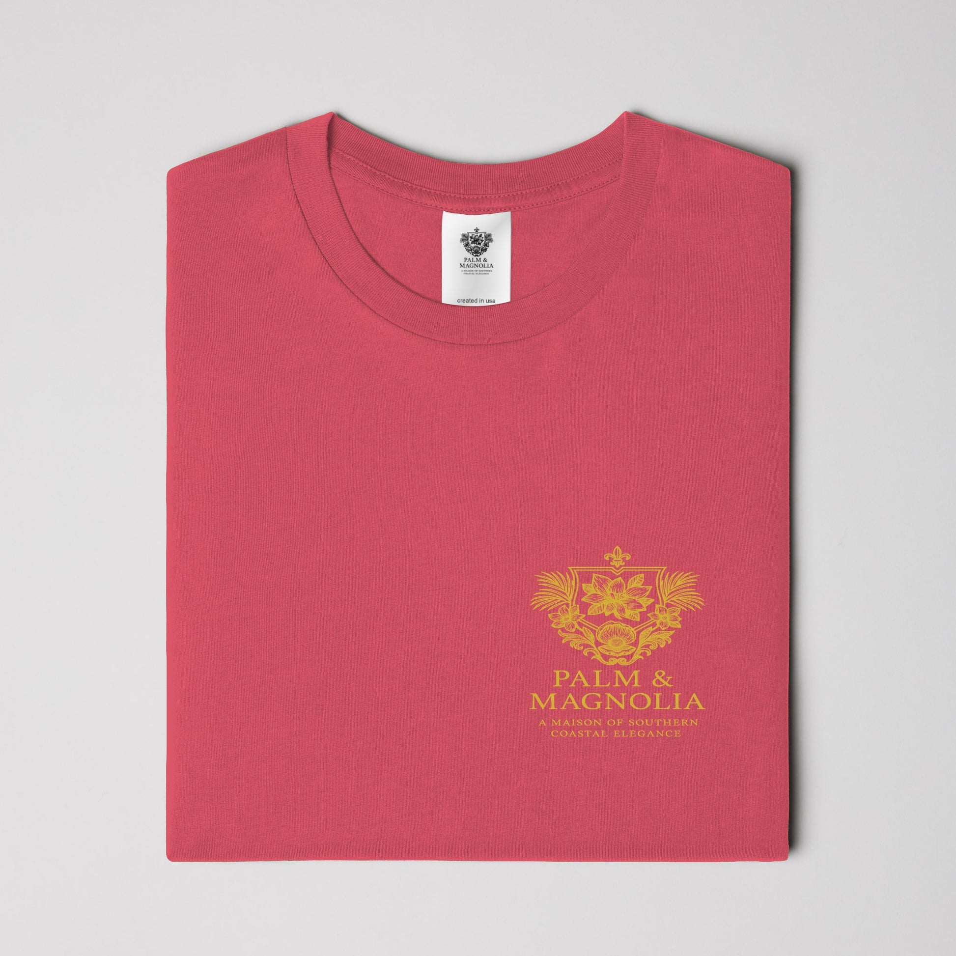 Folded red Comfort Colors heavyweight T-shirt with gold Palm & Magnolia emblem.